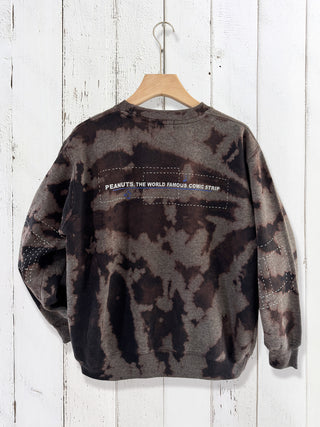 Camouflage-patterned sweatshirt with text on a wooden hanger against a white wooden background
