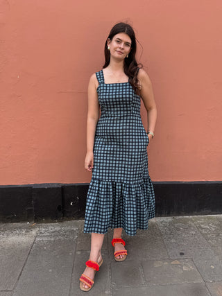 women in check dress stood by wall