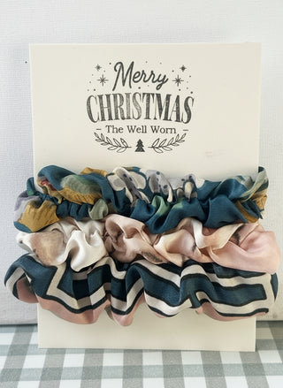 Set of colorful scrunchies on a 'Merry Christmas' card with 'The Well Worn' branding.