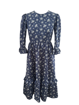 A navy blue long-sleeve midi dress with a white floral print, featuring a gathered waist and ruffled hem, shown against a plain white background.