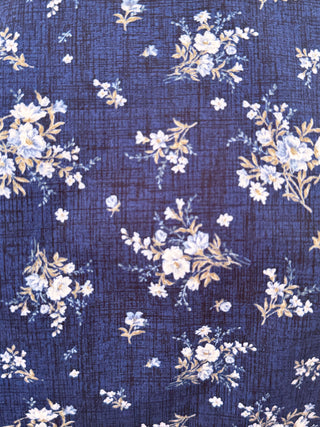 A close-up of a navy blue fabric with a delicate floral pattern in white, light blue, and soft yellow-beige.