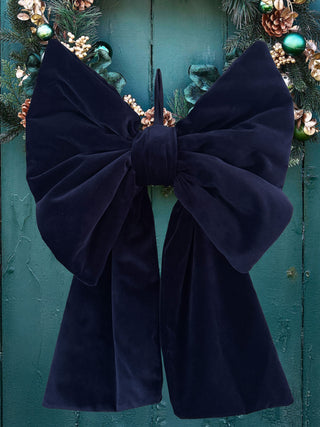 Navy blue velvet bow against a teal background with decorative elements