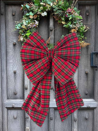 Red plaid bow with greenery on a wooden door