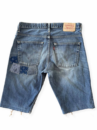 Blue denim shorts with patches on a white background
