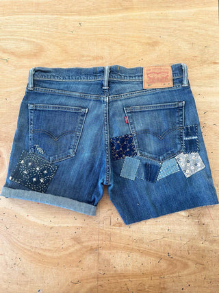 Blue denim shorts with patchwork design on a wooden surface