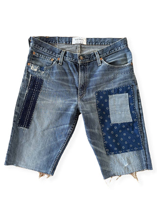 Pair of blue denim shorts with patchwork design on a white background