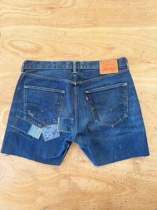 Blue denim shorts with patches on a wooden surface