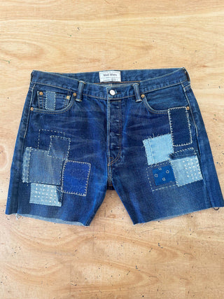 Blue denim shorts with patchwork design on a wooden surface