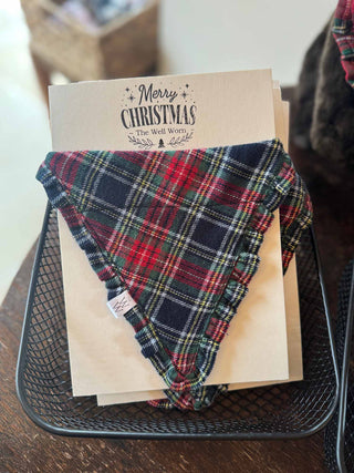 Plaid dog bandana on a Christmas card with 'Merry Christmas' text, placed in a wire basket.