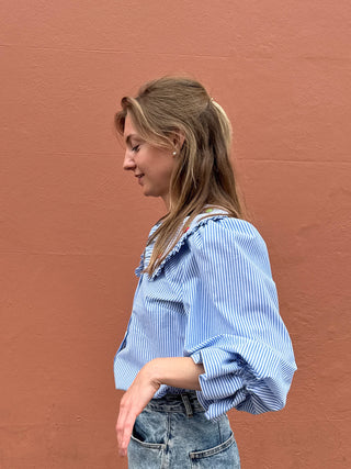 Woman wearing a blue striped shirt against a brown wall