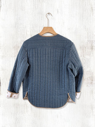 Blue checkered shirt on a wooden hanger against a white wooden background