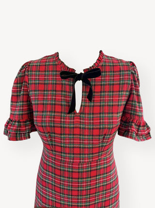 Red and green plaid dress with a black bow on a white background