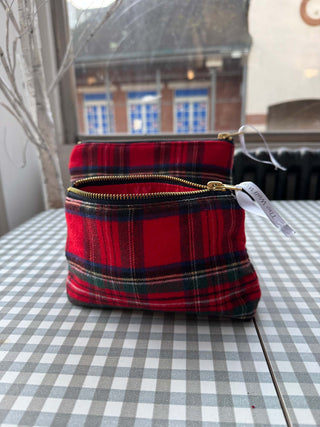 Red plaid pouch with a gold zipper on a checkered tablecloth.