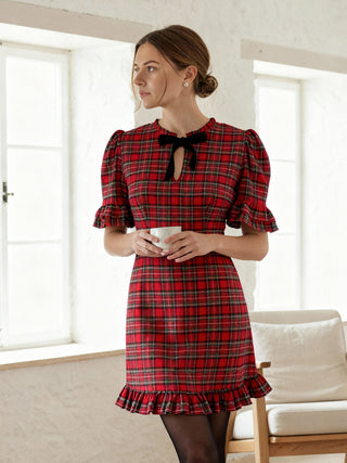 Woman wearing a red plaid dress in a room with white walls and a beige sofa.