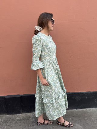 women wearing ruffle midi dress by terracota wall