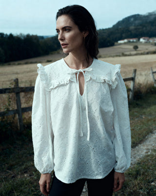 Woman wearing a white blouse with ruffled details in a rural setting