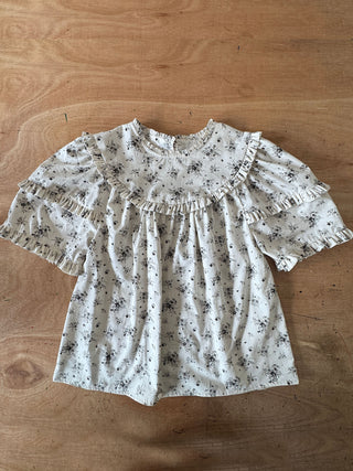 Floral blouse with ruffled sleeves on a wooden surface