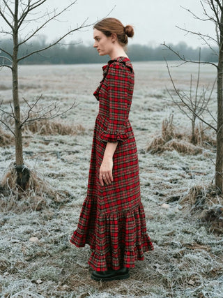Woman in a red plaid dress standing in a frosty field with bare trees.