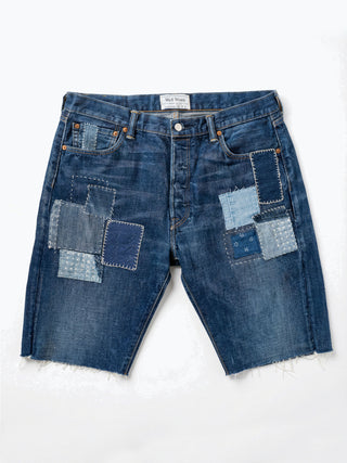 Pair of blue denim shorts with patchwork design on a white background