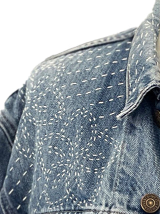 Close-up of a denim jacket with a subtle pattern on a white background