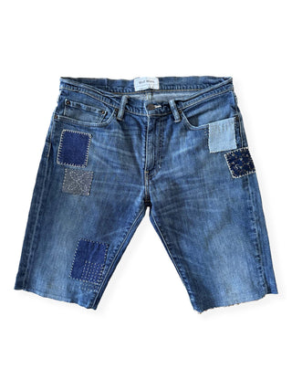 Blue denim shorts with patchwork design on a white background