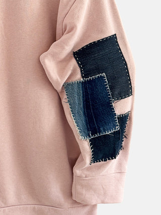 Pink garment with denim patchwork on a plain background