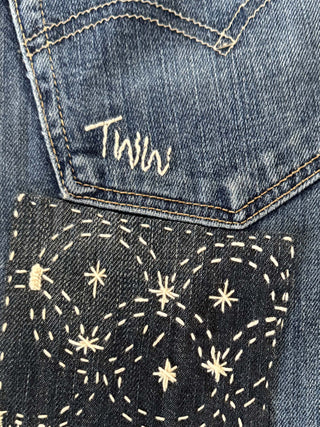 Close-up of a denim pocket with embroidered star patterns and 'Twilio' branding.