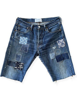 Pair of blue denim shorts with patchwork design on a white background