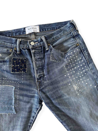 Blue jeans with studded details on a white background