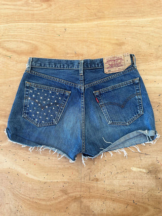 Blue denim shorts with star pattern on a wooden surface