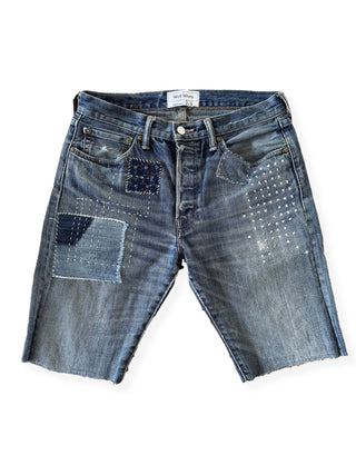 Pair of blue denim shorts with patchwork design on a white background