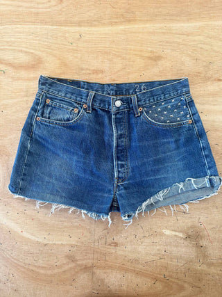 Blue denim shorts with frayed edges on a wooden surface