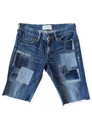 Pair of blue denim shorts with patchwork design on a white background