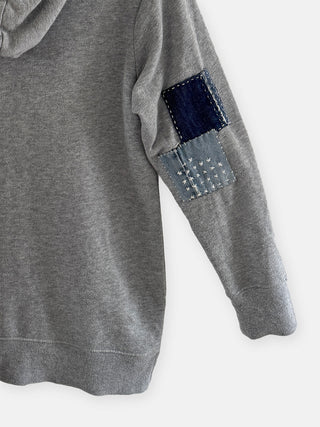 Gray hoodie with denim patch on sleeve against a white background