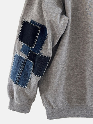 Gray sweater with denim patch details on a white background