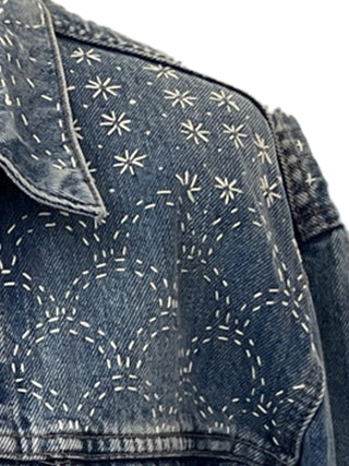 Denim jacket with white geometric stitching pattern on a white background