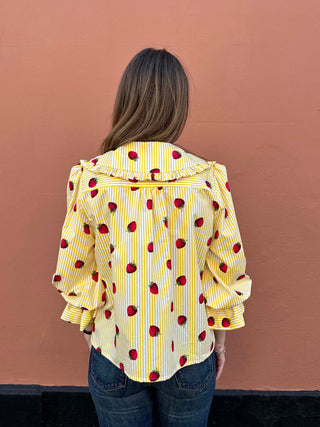 Back view of strawberry print cotton blouse styled with high-waisted denim.