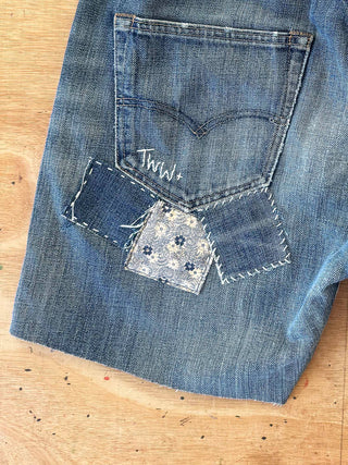 Close-up of blue jeans with a decorative patch on a wooden surface