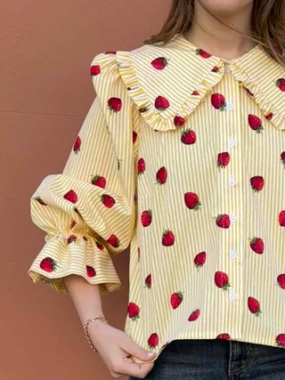 Close-up of strawberry print and gathered sleeve detail on sustainable 100% cotton blouse.