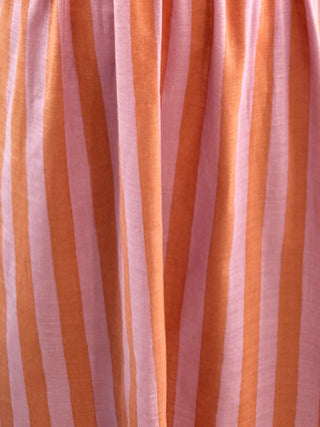 A close-up of a draped fabric with vertical stripes in orange and light pink.