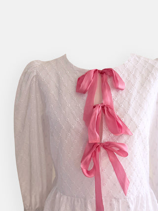White top with pink ribbons on a white background