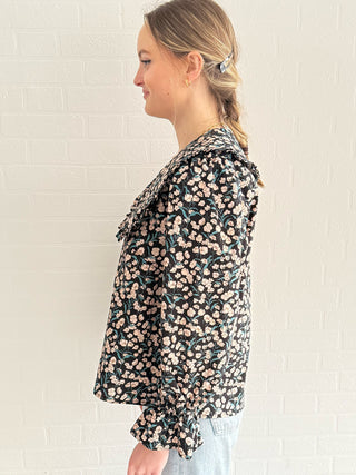 Model wearing navy floral cotton blouse with full-length sleeves and bow details.