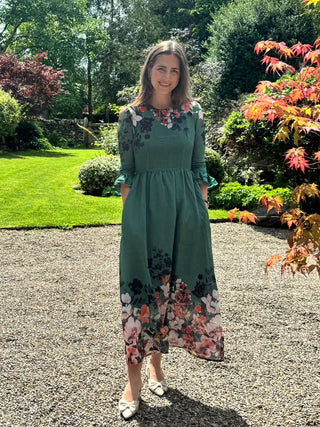Woman in a green floral dress standing in a garden
