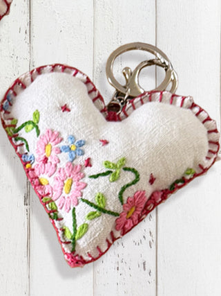 Heart-shaped embroidered keychain on a wooden surface