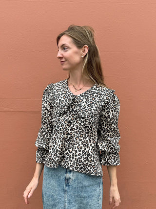 Woman wearing a leopard print blouse against a brown wall