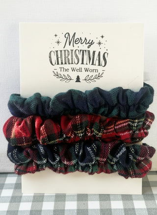 Plaid scrunchies on a card with 'Merry Christmas' text on a checkered background