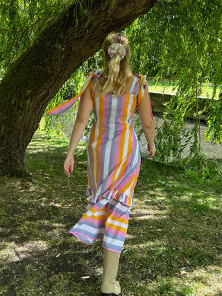 Woman in a colorful striped dress standing under a tree