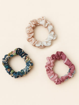 Three colorful scrunchies on a light beige background