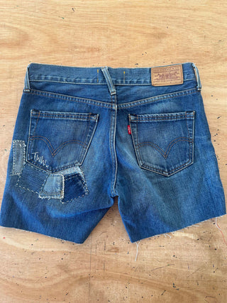 Blue denim shorts with patches on a wooden surface