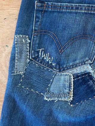 Close-up of blue denim jeans with a brand logo on a wooden surface